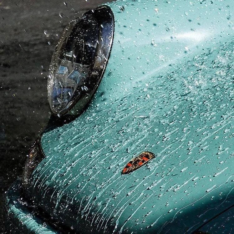 Water beading across a teal performance car.